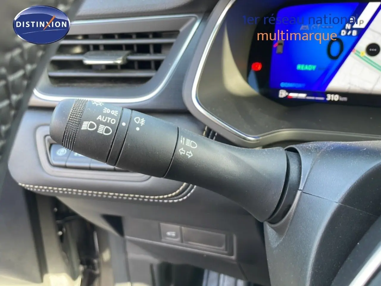 Gros plan sur la commande des feux et clignotants à gauche du volant dans l’habitacle noir du Renault Symbioz gris cassiopée.