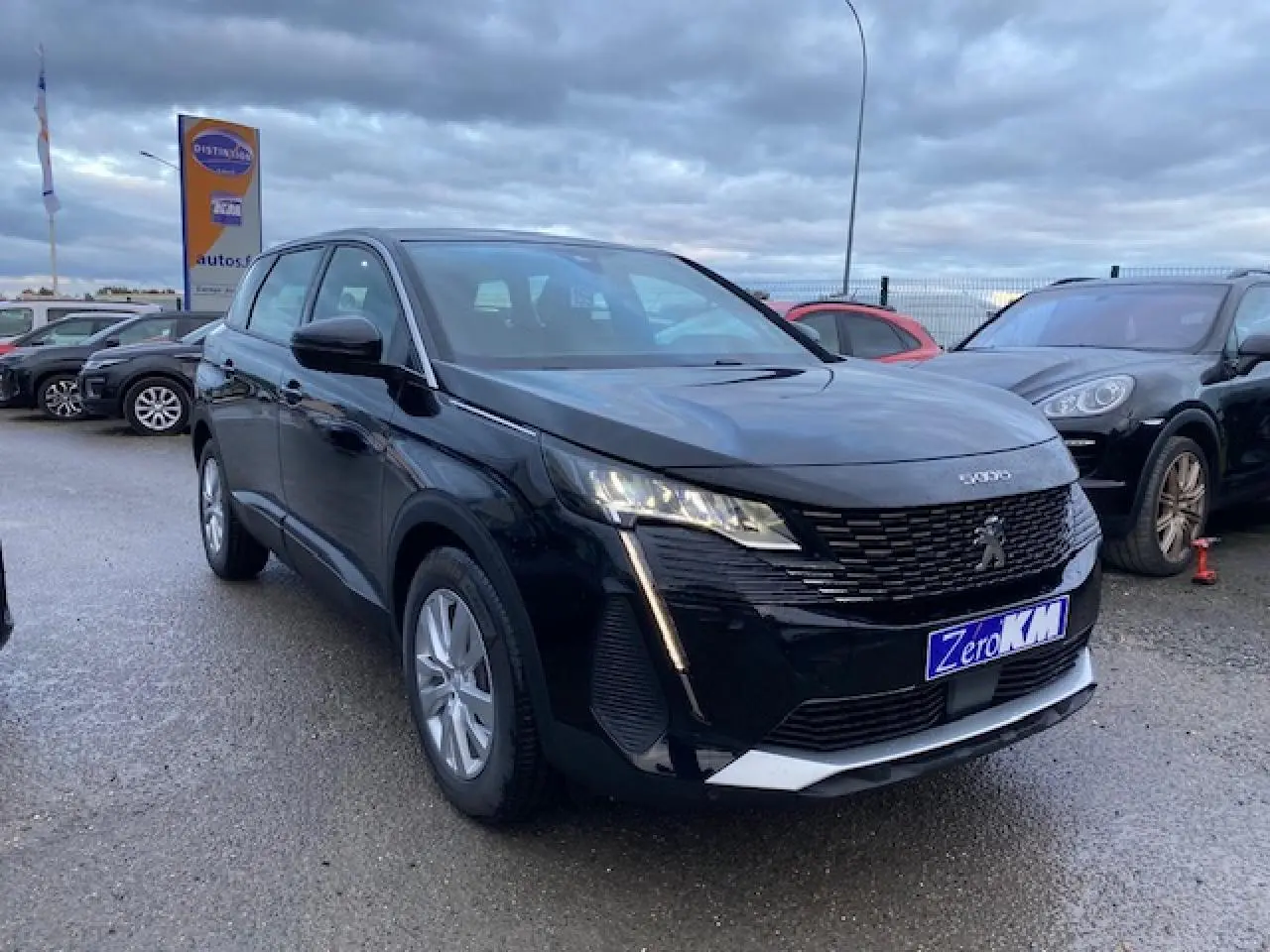 Peugeot 5008 noir vue 3/4 avant droit, avec calandre distinctive et feux LED verticaux allumés.