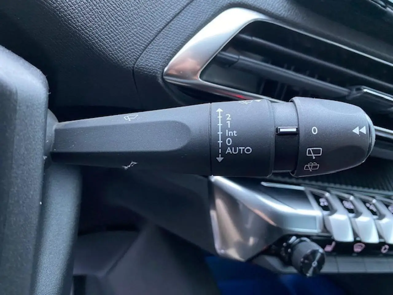Gros plan sur la commande d’essuie-glace à gauche du volant dans l’habitacle noir du Peugeot 5008 2023.