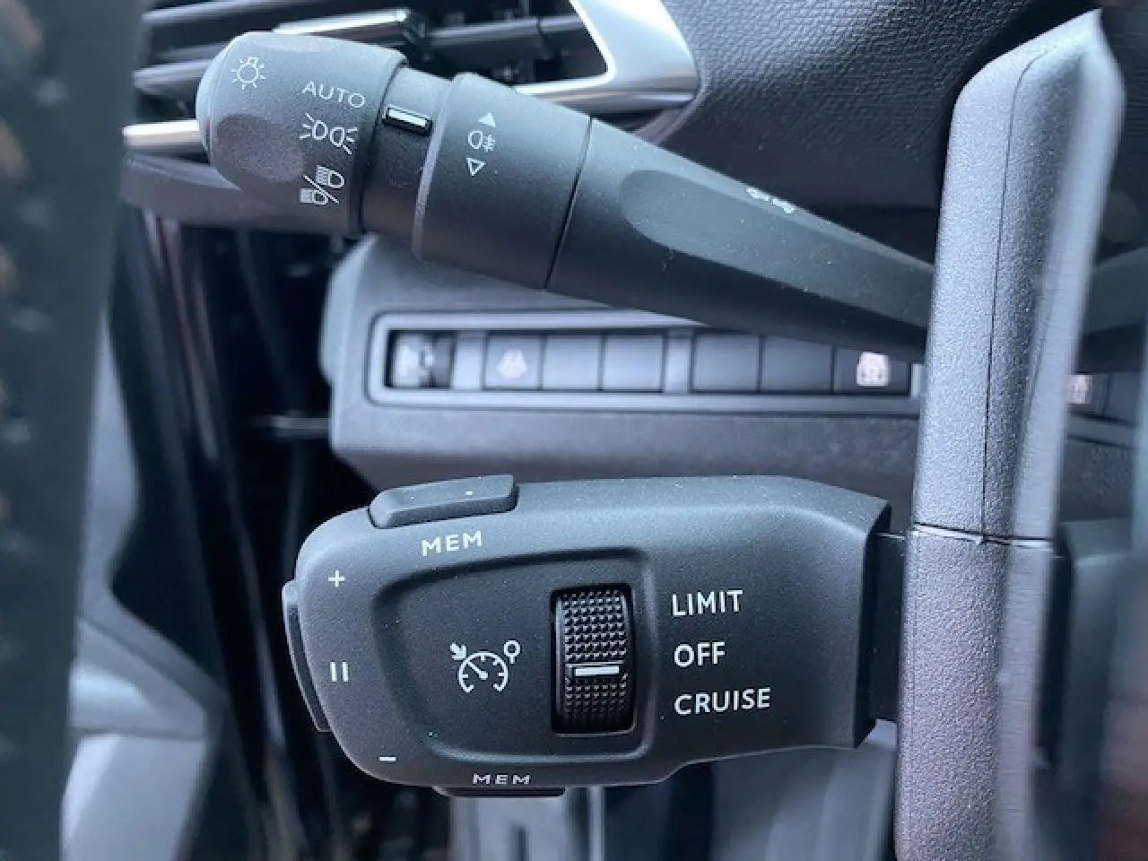 Gros plan sur les commandes du régulateur de vitesse et des feux, intérieur noir du Peugeot 5008 2023.