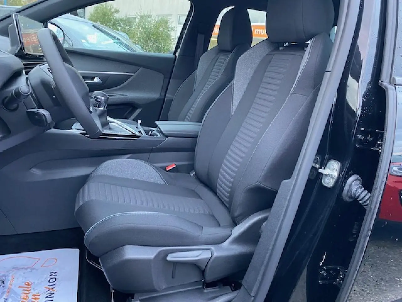 Vue intérieure côté conducteur du Peugeot 5008 noir 2023, mettant en valeur les sièges avant en tissu gris et noir.