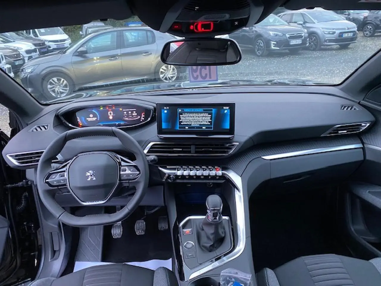Vue intérieure avant du Peugeot 5008 noir 2023, tableau de bord numérique et écran tactile central visible.