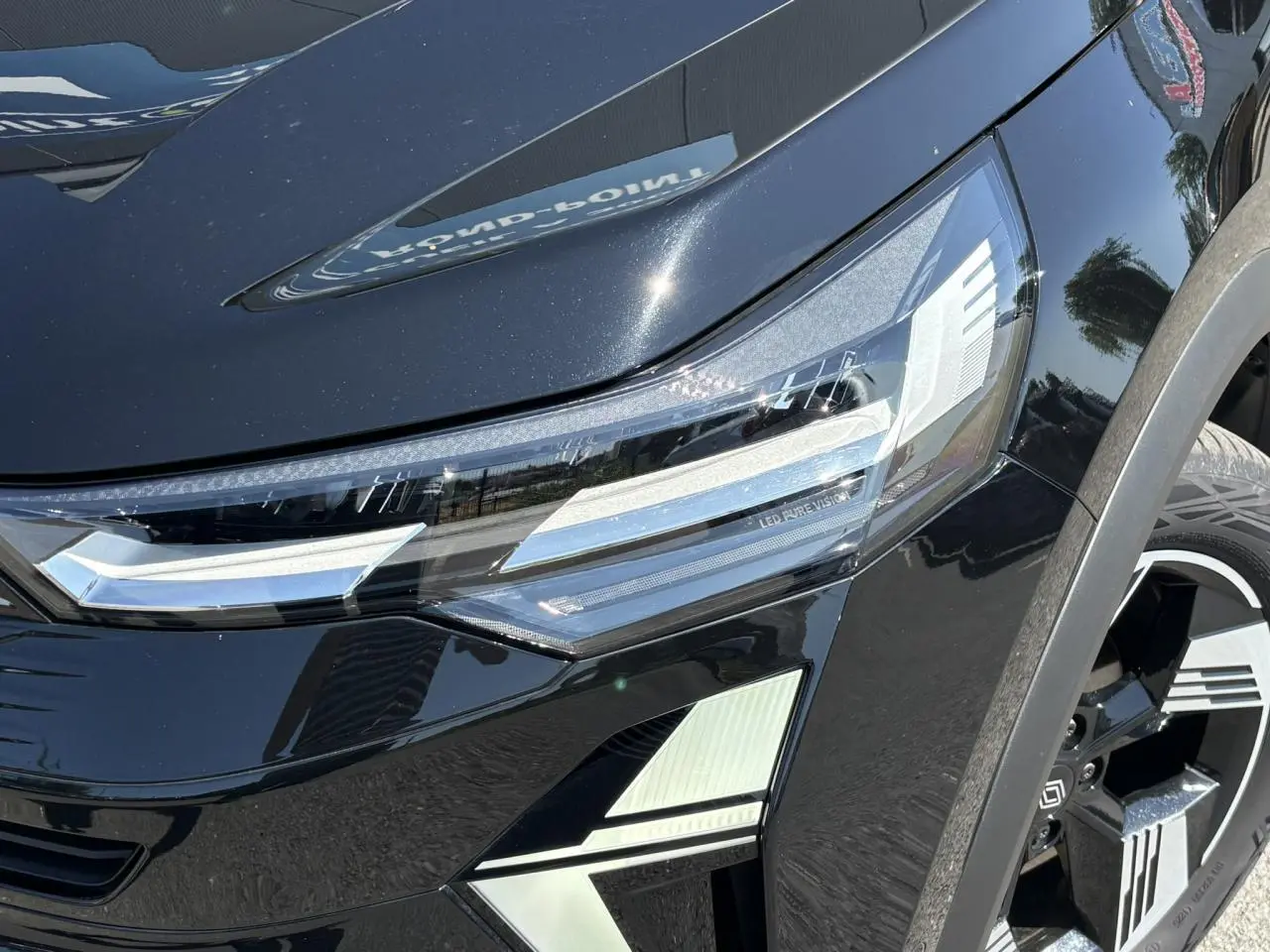 Gros plan sur le phare avant droit et la roue d’une Renault SYMBIOZ noire étoile avec détails LED Pure Vision.