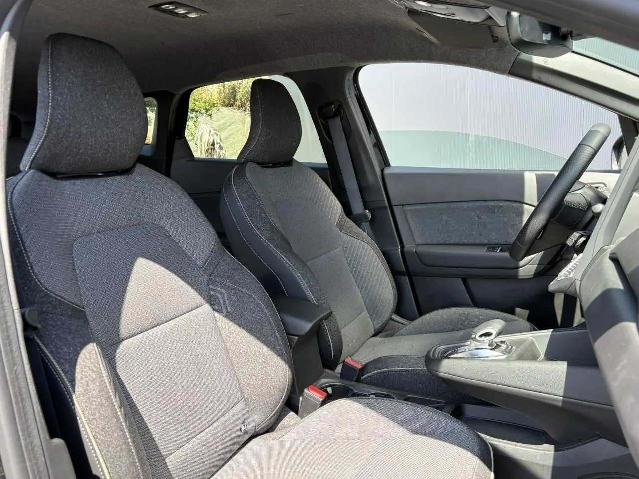 Vue intérieure côté gauche montrant les sièges avant gris foncé et la console centrale du Renault Symbioz E-Tech Full Hybrid 2025.