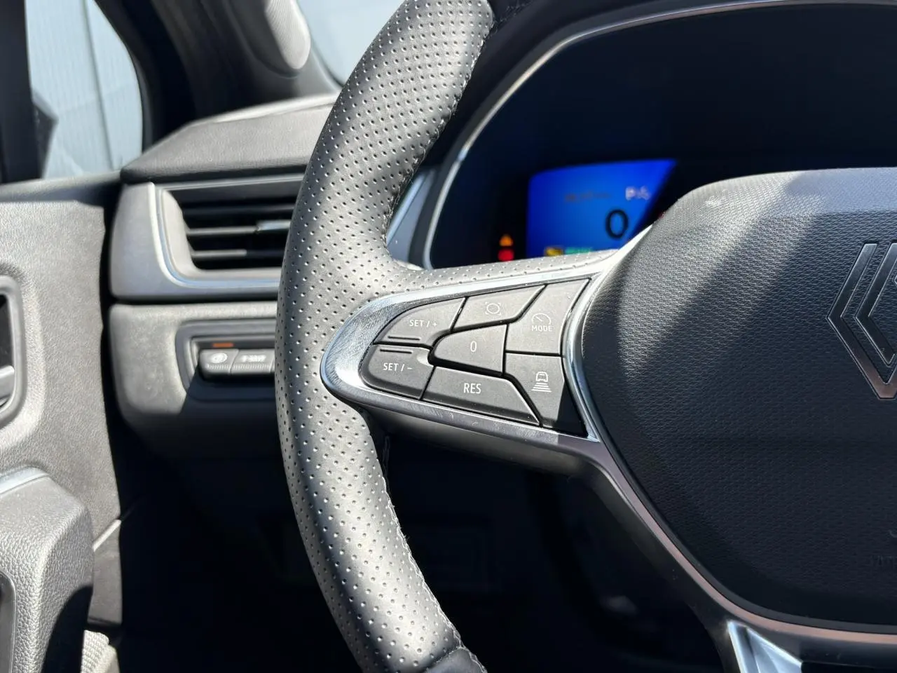 Gros plan sur le volant perforé côté gauche du Renault SYMBIOZ 2025 avec commandes intégrées et tableau de bord numérique.