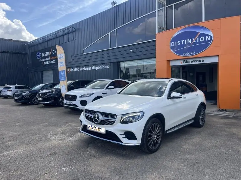 Mercedes GLC Coupé blanc diamant brillant designo, vue 3/4 avant droit devant un concessionnaire Distinxion.