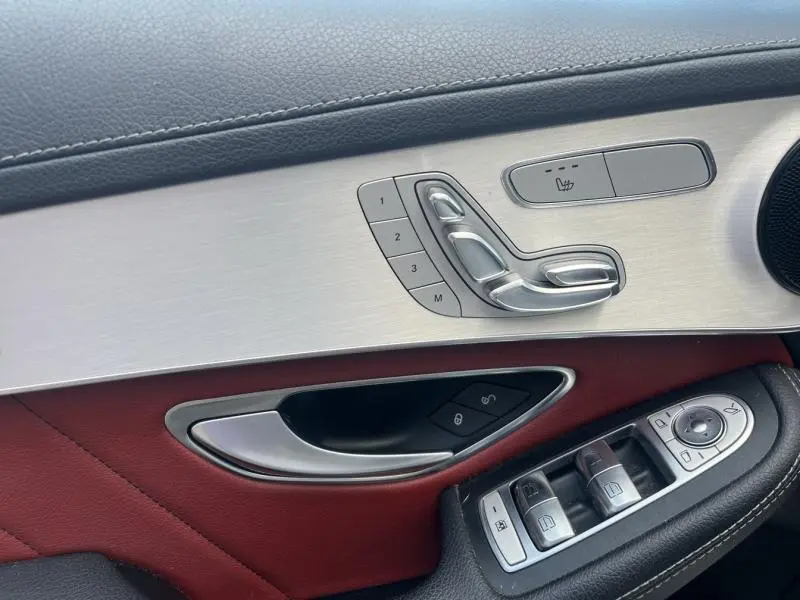 Détail de la porte avant gauche du Mercedes GLC Coupé blanc, avec commandes sièges en aluminium et cuir rouge/noir.