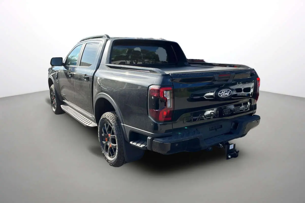 Ford Ranger Wildtrak noir agate vu en 3/4 arrière droit avec benne couverte et jantes tout-terrain.