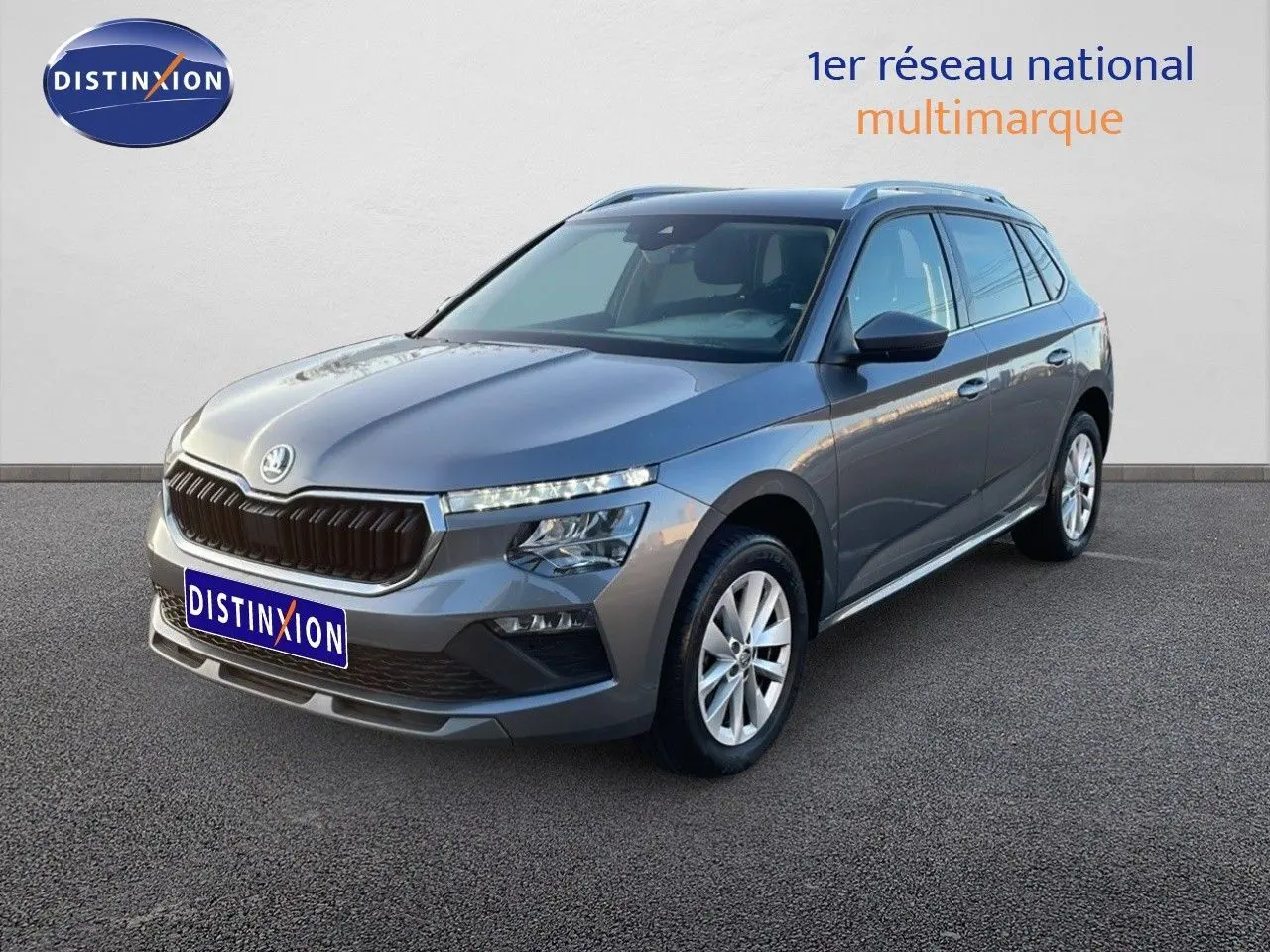 Vue 3/4 avant droite d'un Skoda Kamiq gris graphite métallisé 2024 avec calandre noire et jantes argentées.