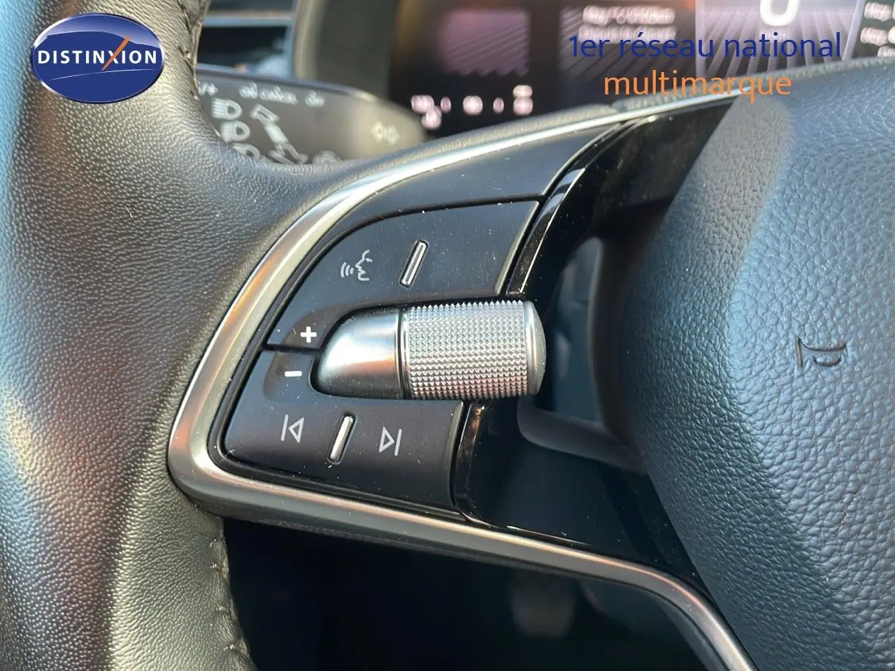 Gros plan sur les commandes audio au volant d'un Skoda Kamiq gris graphite, mettant en valeur la molette métallique texturée.