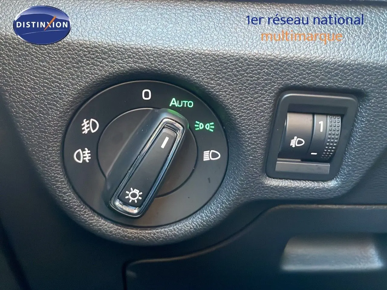 Détail du bouton de commande des phares sur le tableau de bord noir du Skoda Kamiq gris graphite 2024.