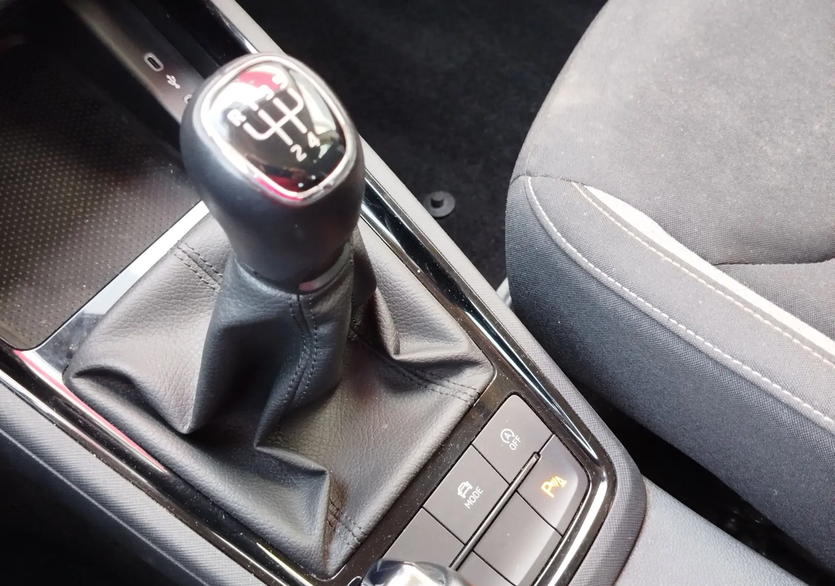 Gros plan sur le levier de vitesses manuel et les commandes de la console centrale du Skoda Kamiq 2024, intérieur tissu gris noir.