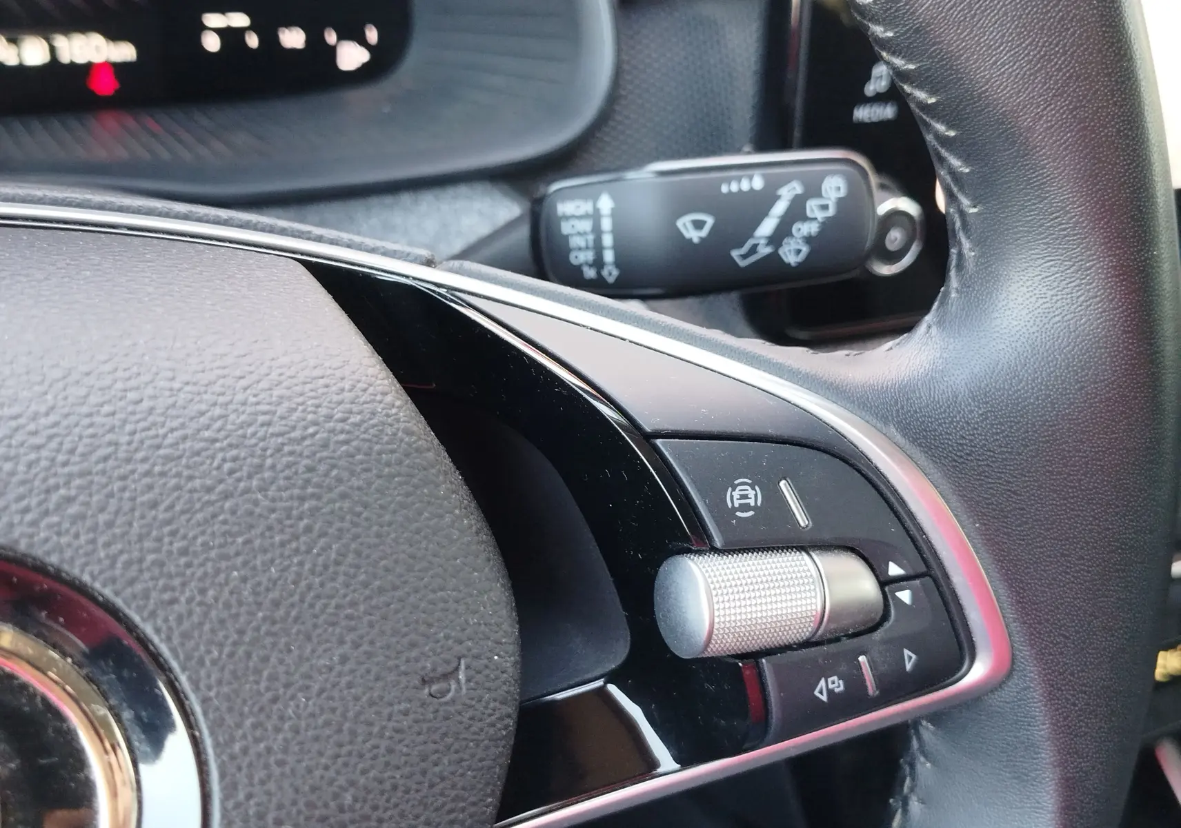 Gros plan sur la commande multifonction argentée et noire du volant du Skoda Kamiq 2024, intérieur cuir noir.