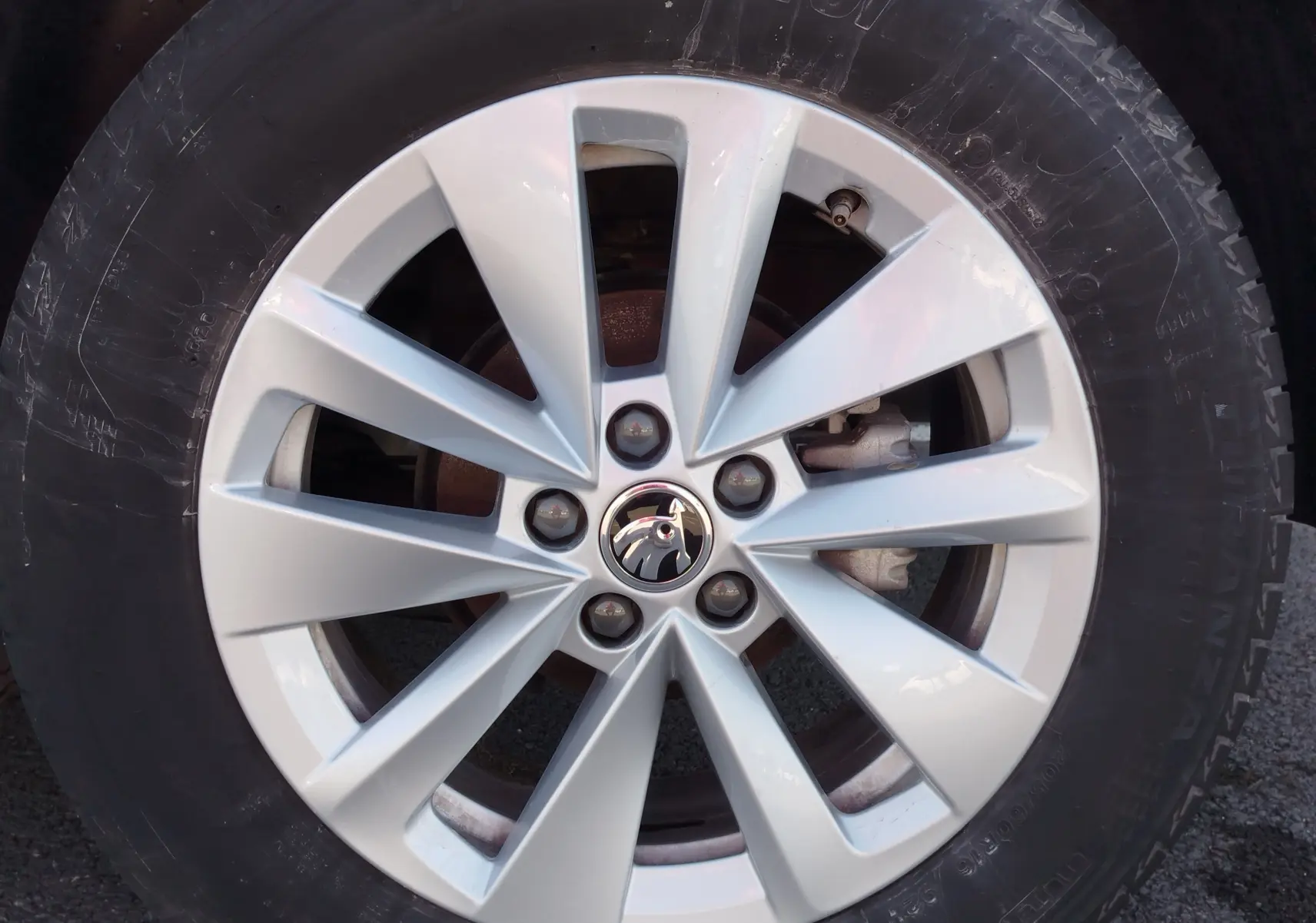 Gros plan sur la jante argentée en alliage du Skoda Kamiq 2024 avec logo au centre, entourée d’un pneu noir.