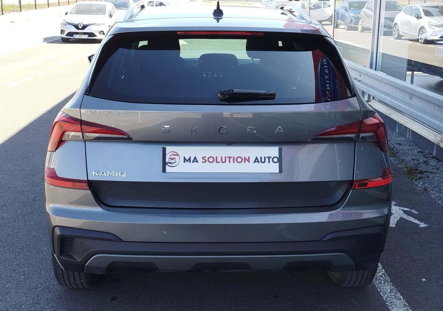 Vue arrière d'un Skoda Kamiq gris graphite métal 2024 avec feux LED et hayon fermé sur parking extérieur.