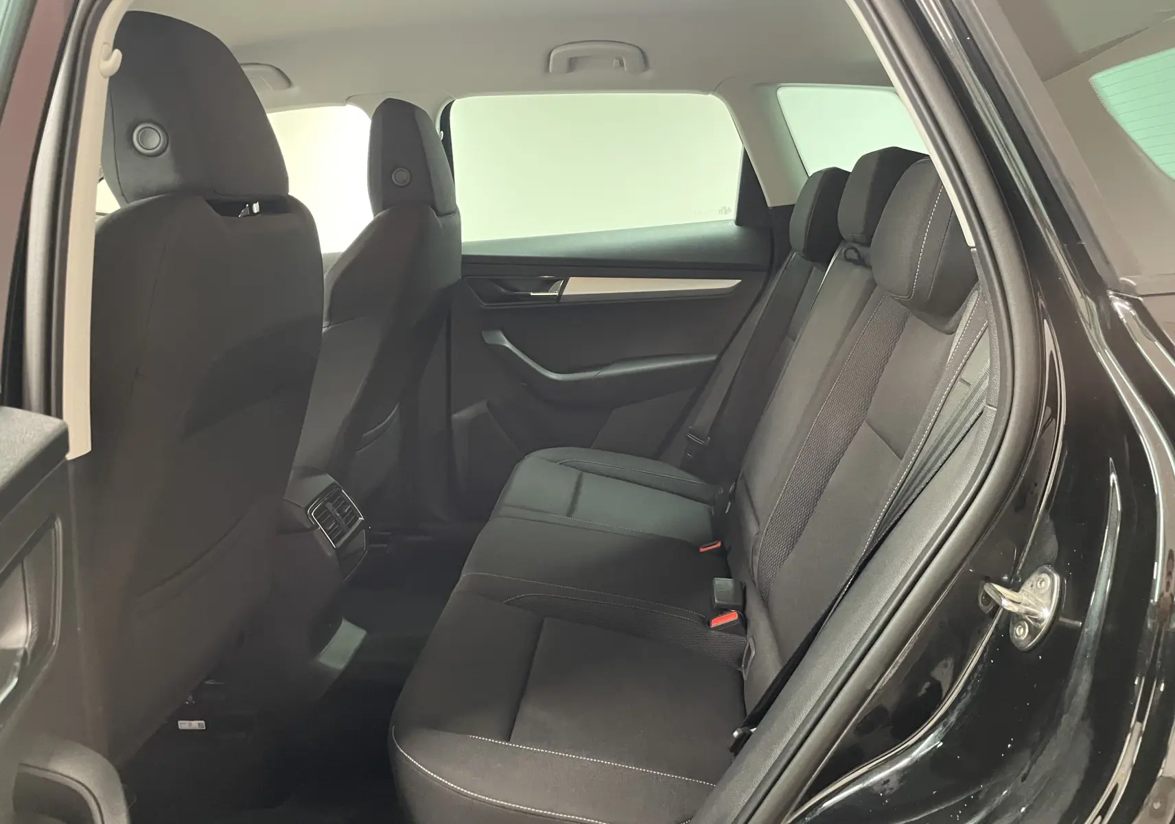 Intérieur arrière du Skoda Karoq noir Magic nacré, vue côté droit avec sièges tissu noirs et appuie-têtes réglables.