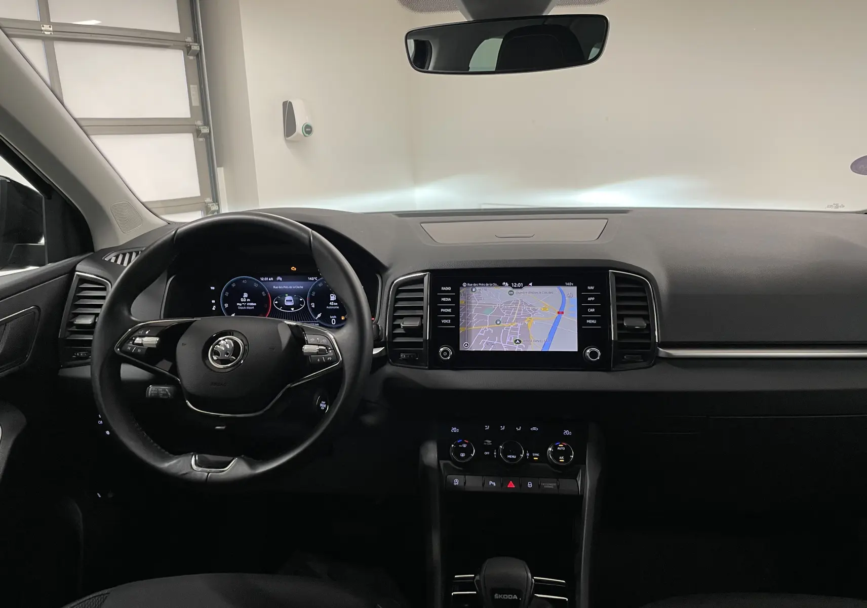 Intérieur du Skoda Karoq 2023 avec tableau de bord noir, écran tactile central affichant une carte et volant multifonction.