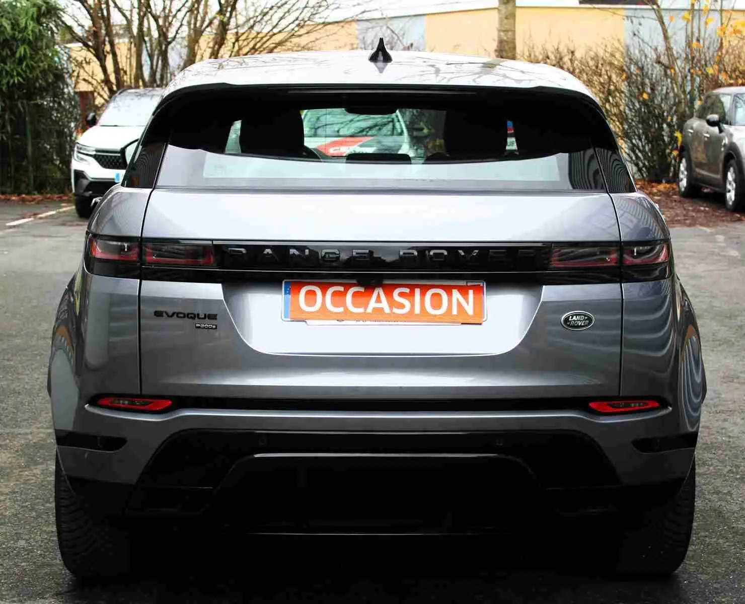 Vue arrière d'un Range Rover Evoque gris métal 2023 avec logo Land Rover et plaque "OCCASION" visible.