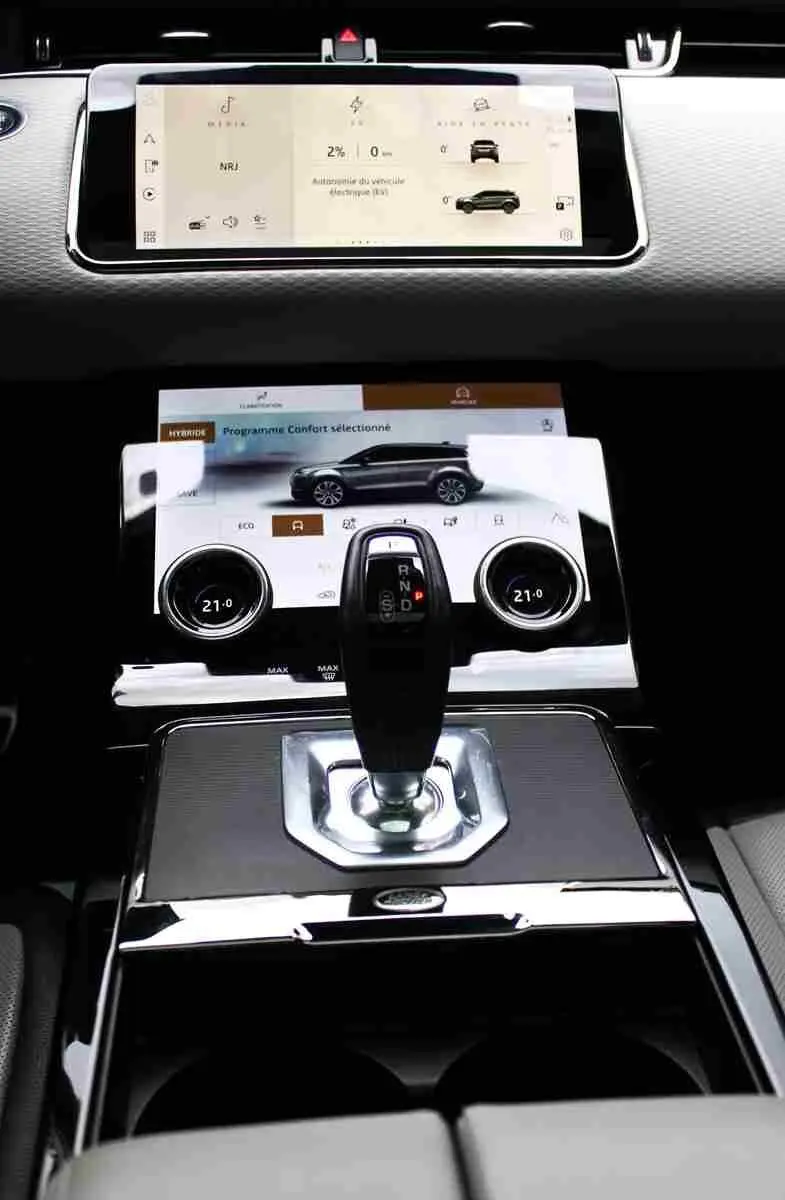 Vue rapprochée de la console centrale du Range Rover Evoque gris métal 2023 avec écran tactile et levier de vitesse moderne.