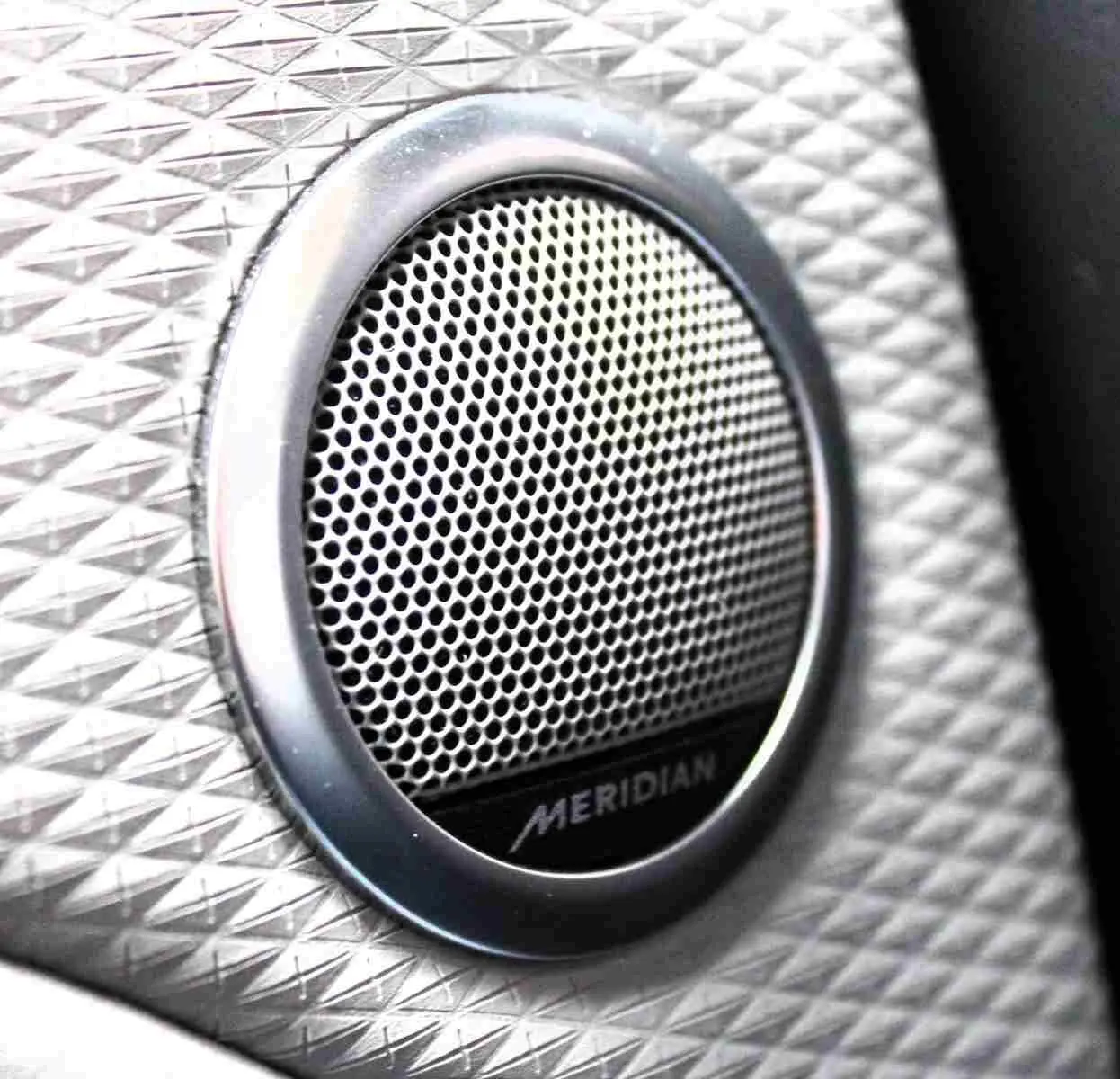 Gros plan sur l'enceinte audio Meridian intégrée dans l'habitacle du Range Rover Evoque 2023 gris métal.