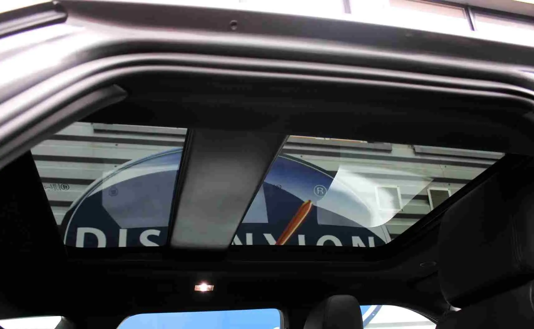 Toit panoramique ouvert du Range Rover Evoque gris métal 2023, vue intérieure arrière avec sièges en cuir noir.