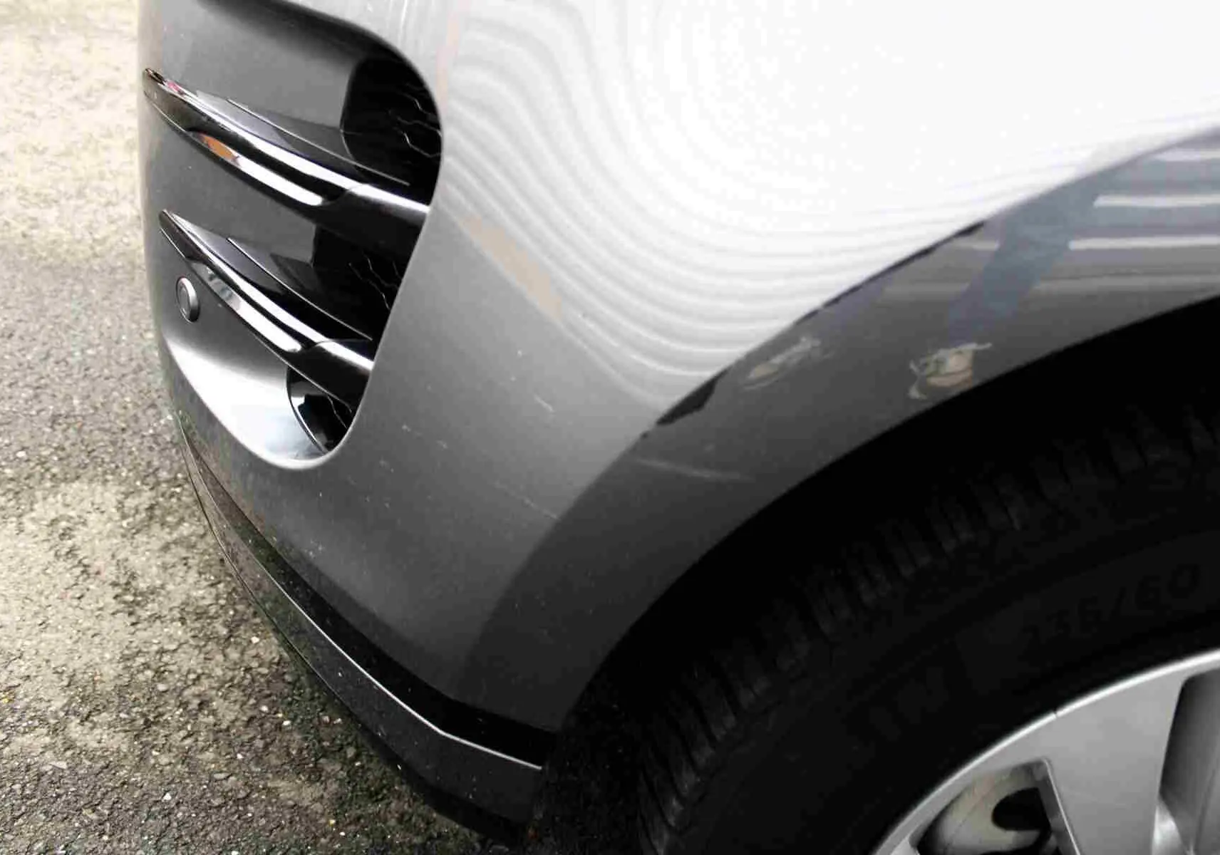 Gros plan sur l'aile avant droite gris métal du Range Rover Evoque 2023 avec prise d'air et partie de la roue visible.