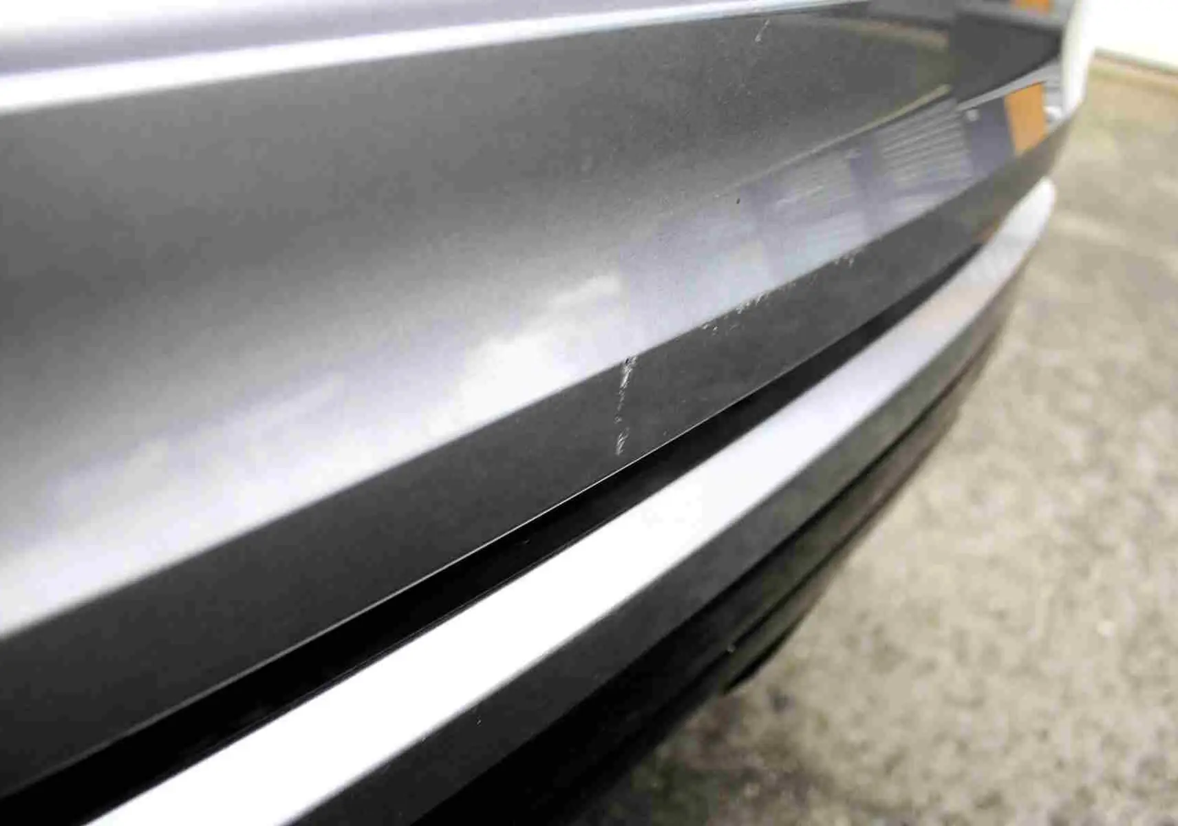 Gros plan sur la partie arrière grise métallisée du Range Rover Evoque 2023, montrant une rayure visible sur la carrosserie.