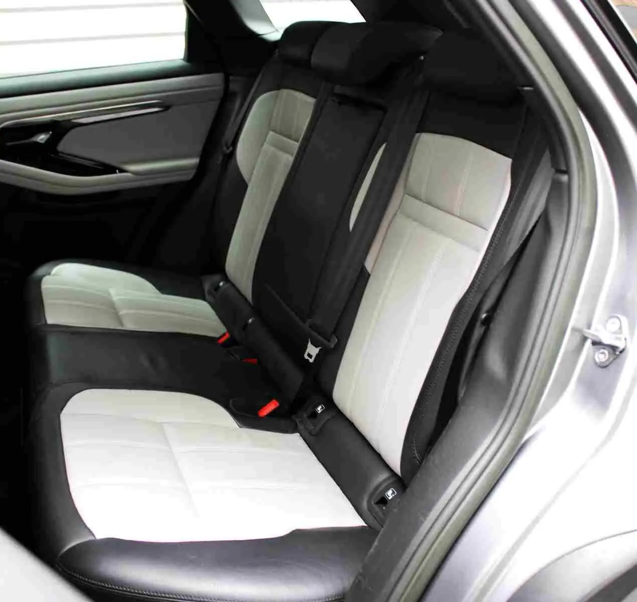Vue intérieure côté gauche des sièges arrière bicolores noir et blanc du Range Rover Evoque gris métal 2023 hybride rechargeable.