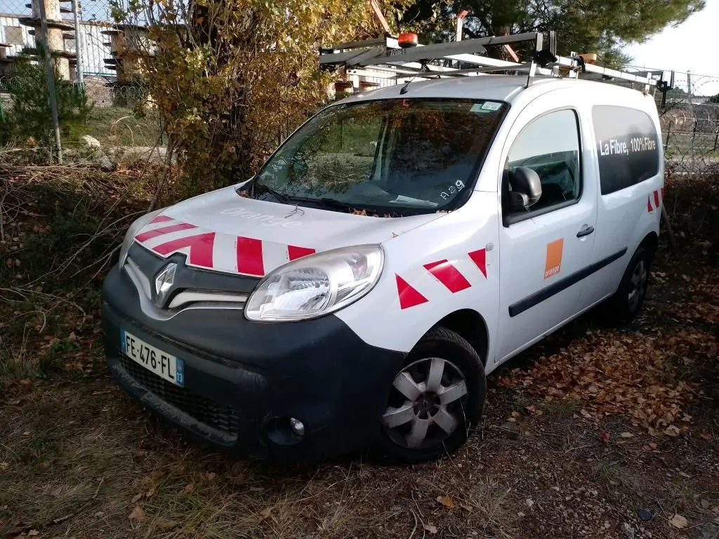 Renault Kangoo blanc vue 3/4 avant droit avec bandes rouges réfléchissantes sur capot et portières.