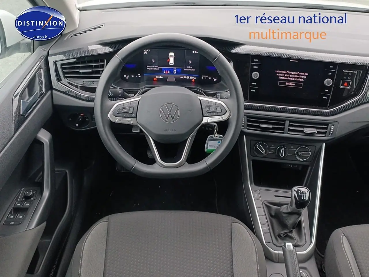 Vue intérieure centrée sur le volant multifonction et la console avec levier de vitesses manuelle d'une Volkswagen Polo blanche.