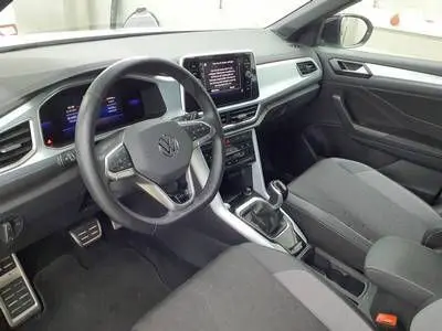 Vue intérieure du Volkswagen T-Roc 2025 montrant le tableau de bord, le volant multifonction et l'écran central tactile.