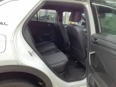 Vue intérieure côté gauche arrière du Volkswagen T-Roc blanc avec sièges arrière en tissu et portières ouvertes.