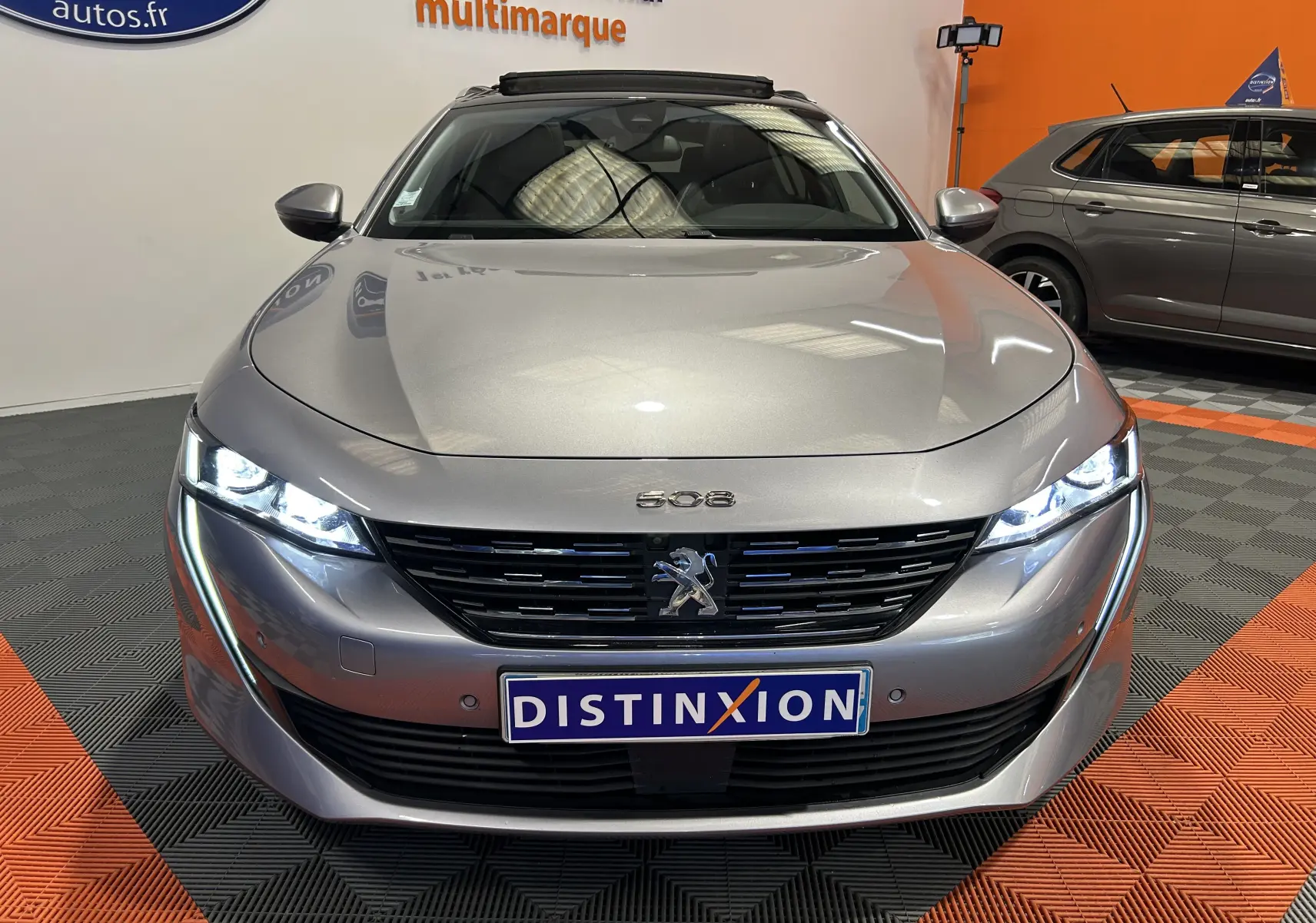 Peugeot 508 SW gris Platinium vue de face avec phares LED allumés et calandre noire distinctive.