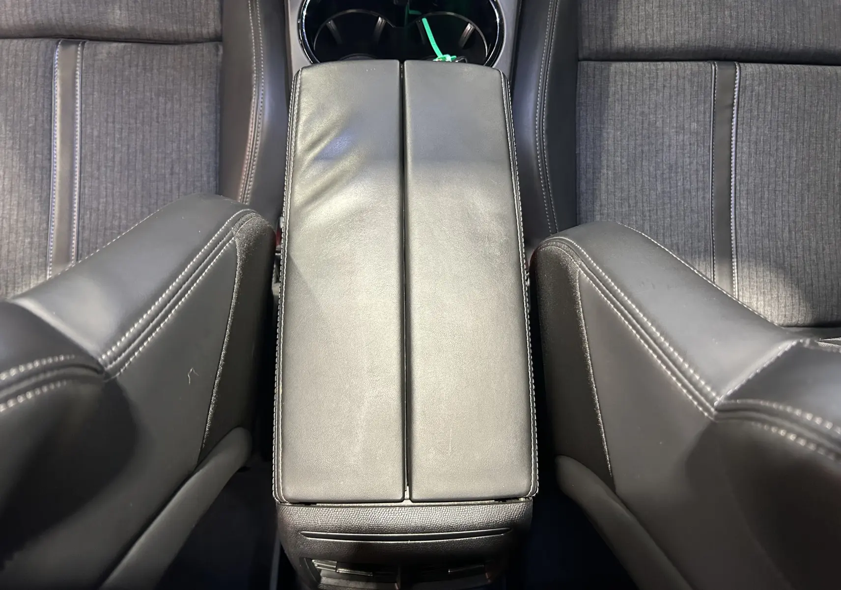 Vue plongeante sur l'accoudoir central en cuir noir et les sièges avant en tissu gris du Peugeot 508 SW 2019.