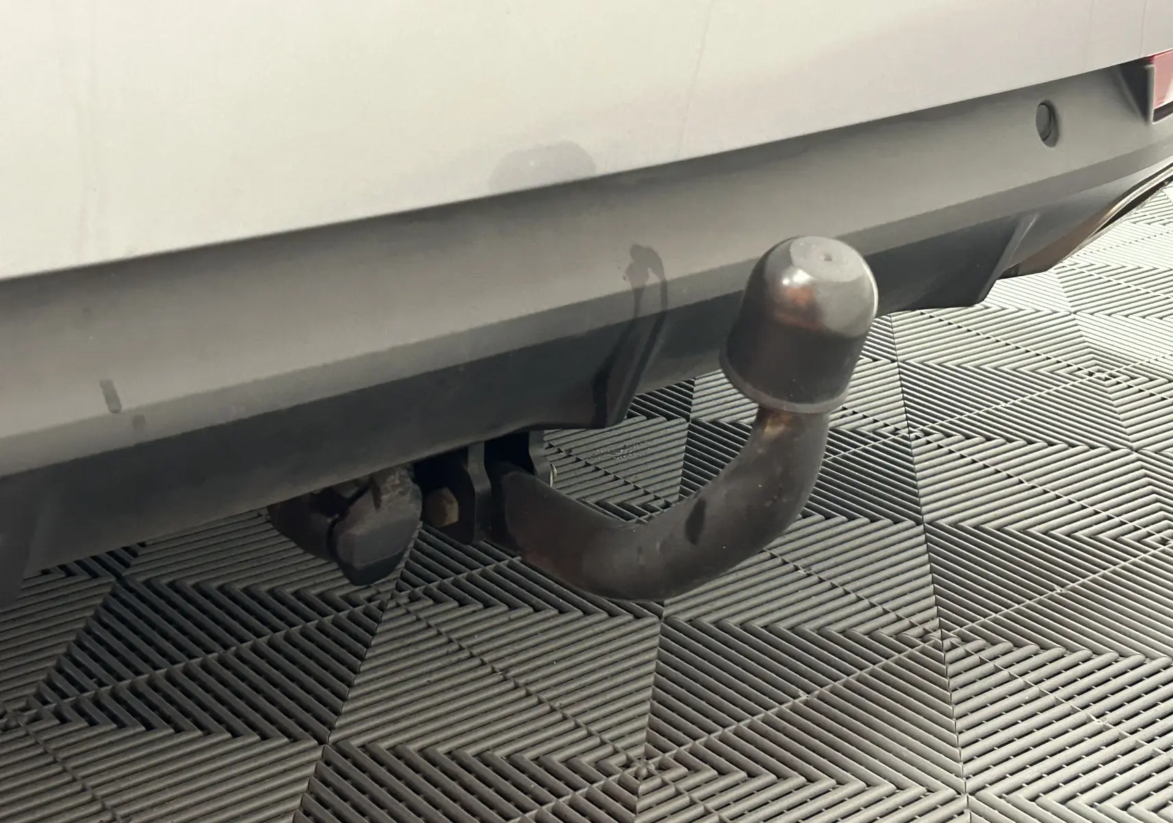 Gros plan sur l'attelage arrière d'une Peugeot 508 SW gris Platinium, avec protection en caoutchouc sur la boule.