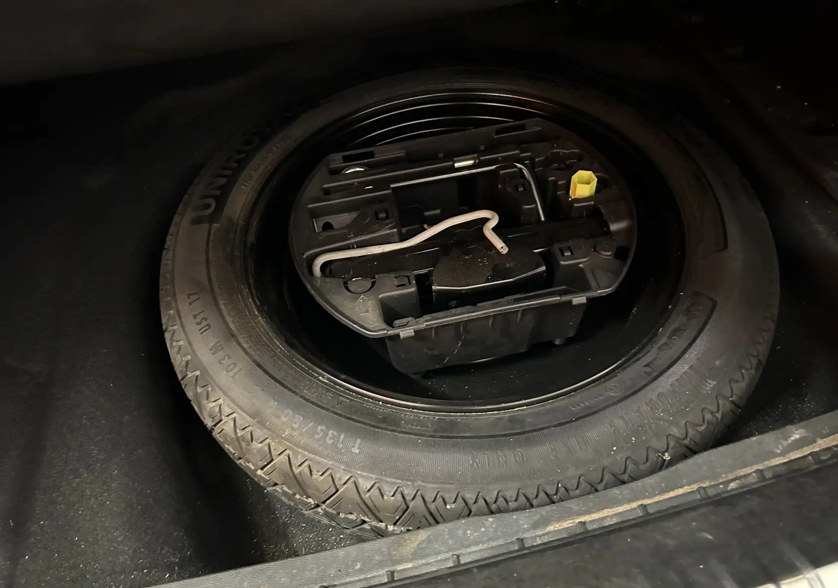 Gros plan sur la roue de secours et son kit d'outils dans le coffre d'une Peugeot 508 SW gris Platinium.