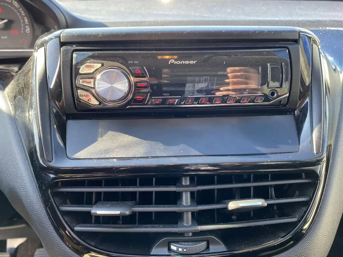 Vue rapprochée de l’autoradio Pioneer noir intégré au tableau de bord d’une Peugeot 208 noire.