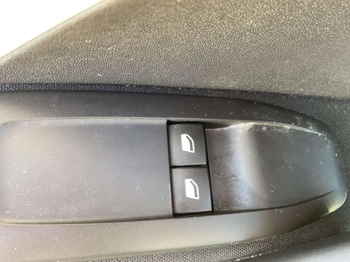 Gros plan sur les commandes de lève-vitres électriques côté conducteur de la Peugeot 208 noire de 2015.