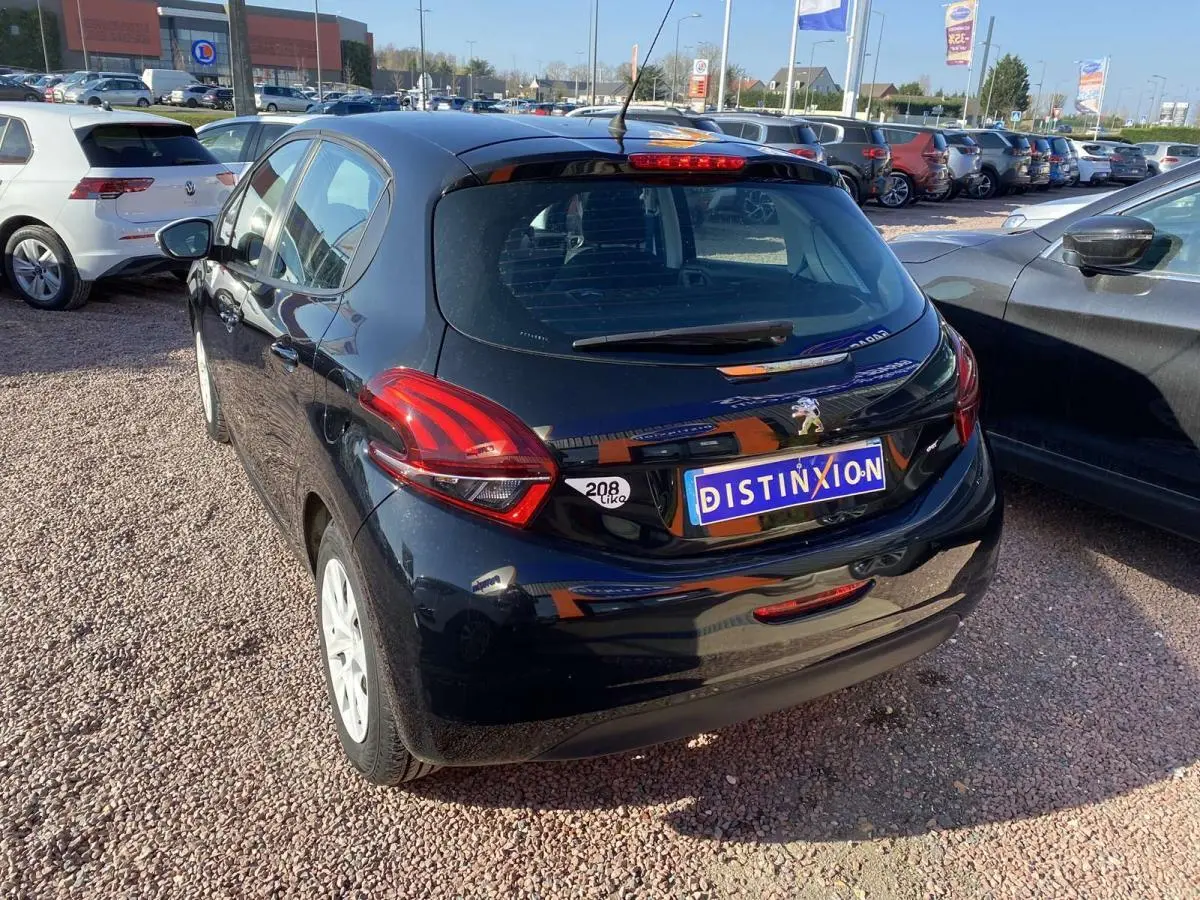 Peugeot 208 noire vue 3/4 arrière droit, avec jantes blanches et feux arrière distinctifs en forme de griffes.