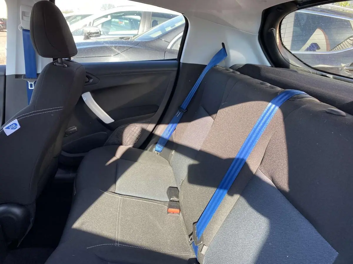 Vue intérieure côté droit montrant la banquette arrière noire avec ceintures de sécurité bleues sur Peugeot 208 2015.