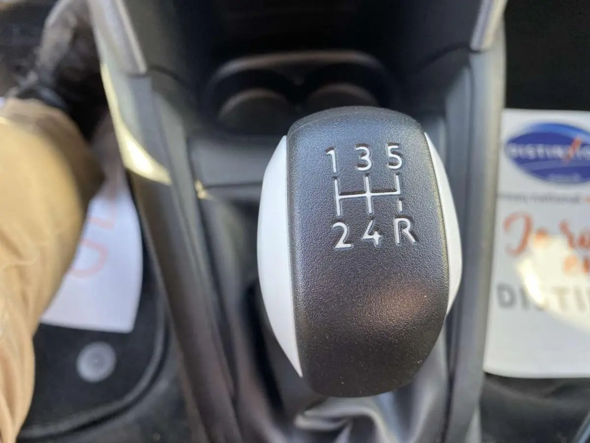 Gros plan sur le levier de vitesses manuel noir et blanc de la Peugeot 208 essence, vue intérieure centrée.