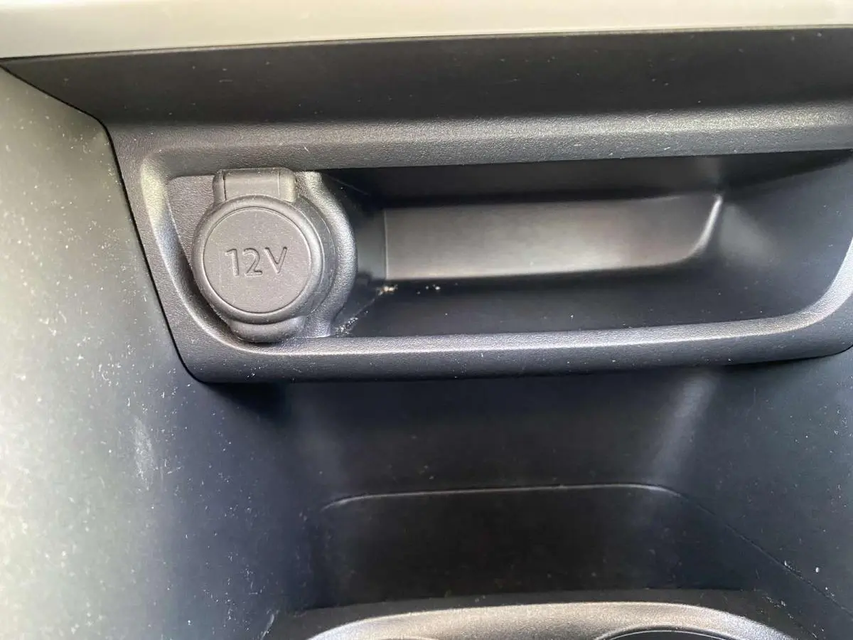 Gros plan sur la prise 12V noire dans le compartiment intérieur du Peugeot 208 noir, version Like 2015.