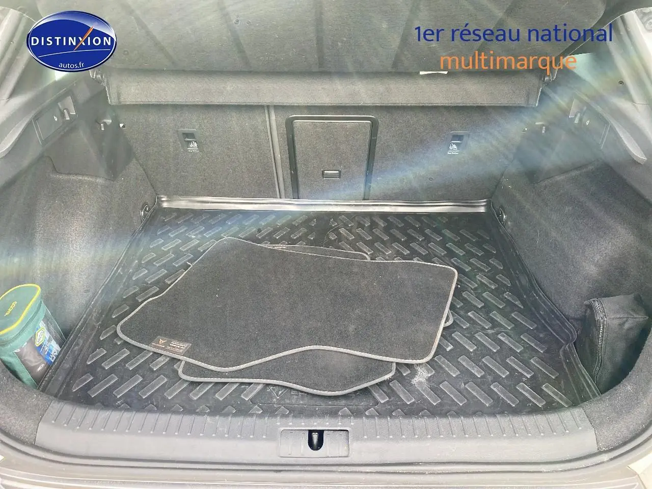 Coffre ouvert vu de l'arrière d'une CUPRA Formentor blanc avec tapis de sol noirs et rangement organisé.