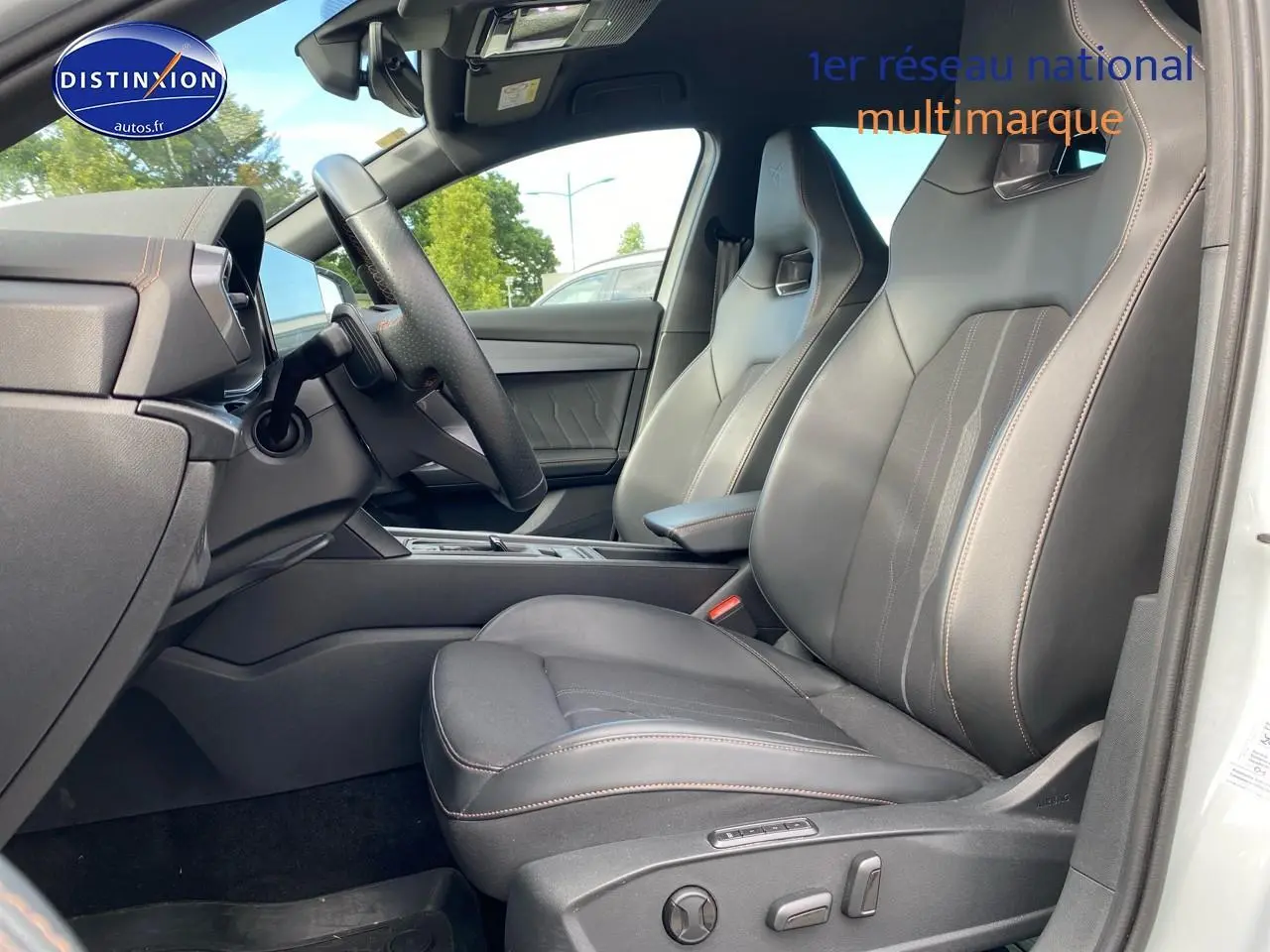 Vue intérieure côté conducteur du CUPRA Formentor blanc 2023, sièges sport en tissu et similicuir noir avec surpiqûres cuivre.