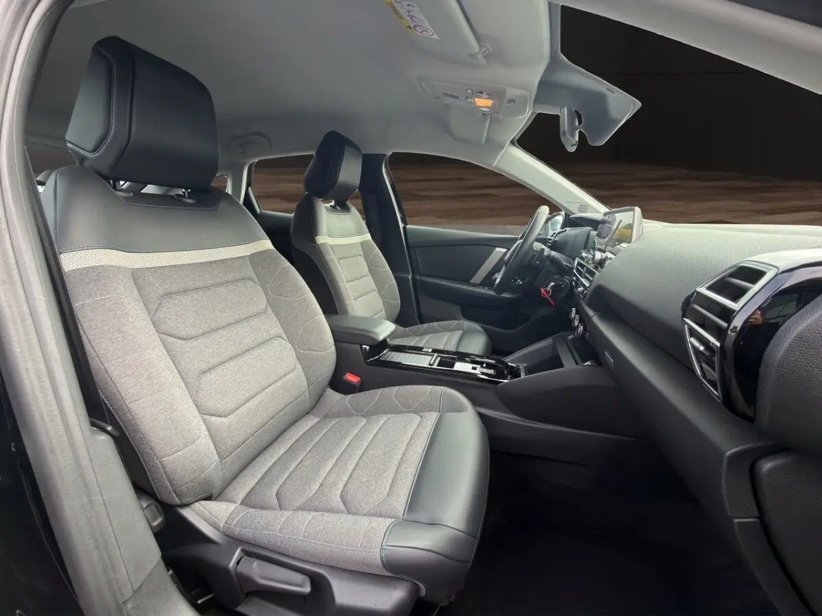 Intérieur de la Citroën C4 2023 noir, vue côté gauche avant, sièges tissu gris avec appuis-tête cuir noir.