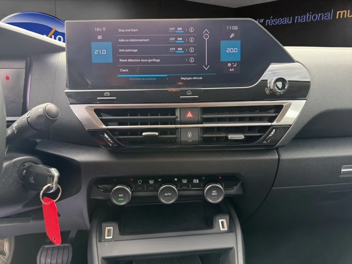 Vue rapprochée du tableau de bord central tactile noir de la Citroën C4 2023 avec commandes climatisation et affichage digital.