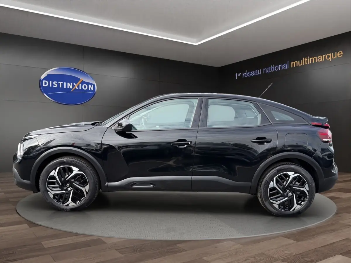 Profil côté gauche d'une Citroën C4 noire 2023 avec jantes distinctives et lignes fluides, en intérieur showroom.