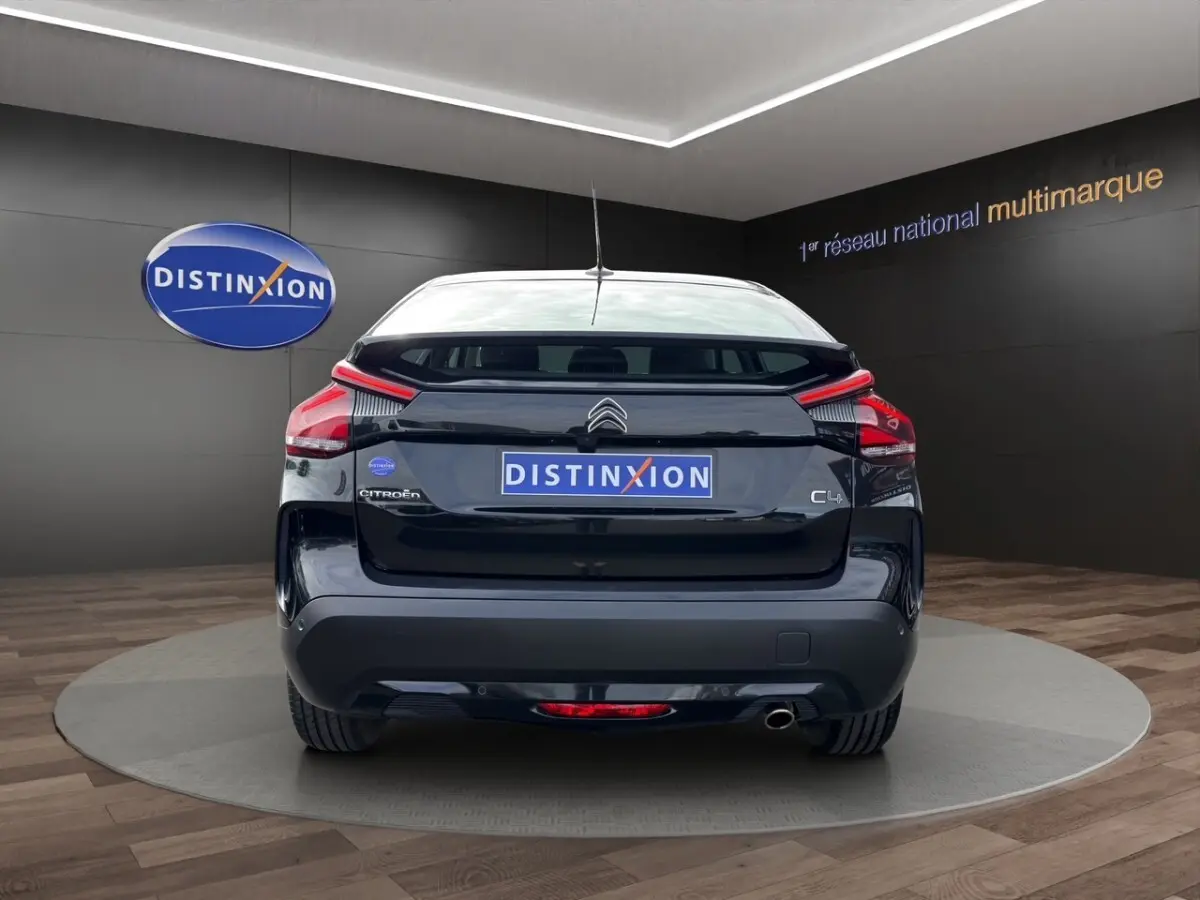 Vue arrière d'une Citroën C4 noire 2023 avec feux LED et sortie d'échappement visible en showroom.
