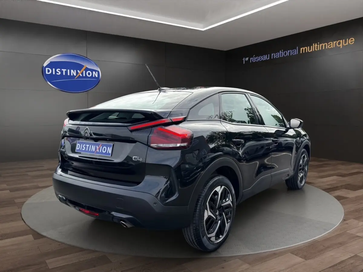 Vue 3/4 arrière droite d'une Citroën C4 noire 2023 avec toit incliné et feux arrière LED distinctifs.