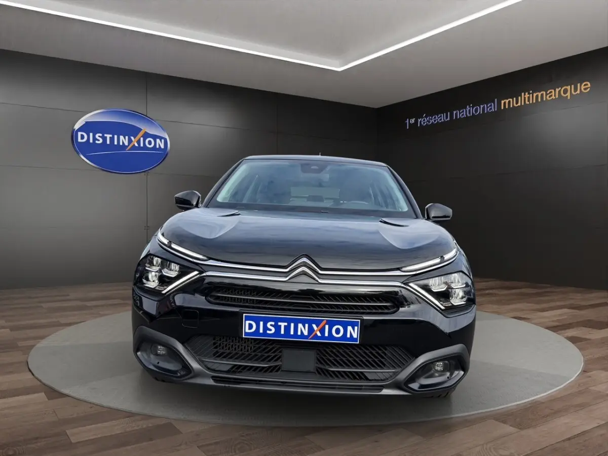 Citroën C4 noir vue de face dans un showroom avec calandre chromée et phares LED distinctifs.